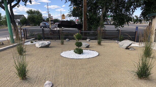 Zona ajardinada con grava, rocas y plantas pequeñas.