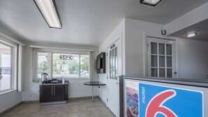 Un vestíbulo de hotel con mostrador de recepción, una estación de café y un gran cartel que anuncia un motel.