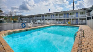 A swimming pool with a brick border, a fenced area with lounge chairs, and a motel building in the background. - Motel 6 Chattanooga, TN (Chattanooga)