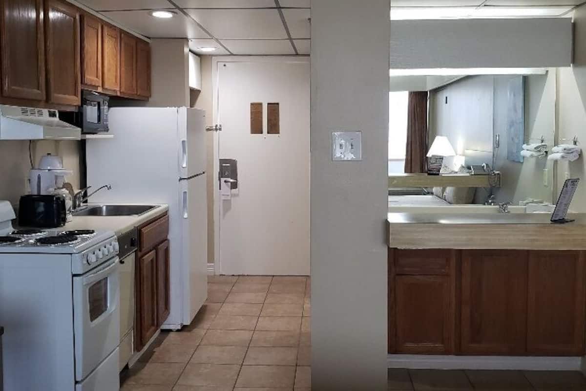 A kitchen with a stove, microwave, refrigerator, and wooden cabinets.