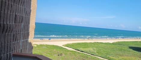 A balcony with a view of a beach and ocean.