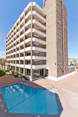Ein mehrstöckiges Hotel mit Schwimmbecken davor.
