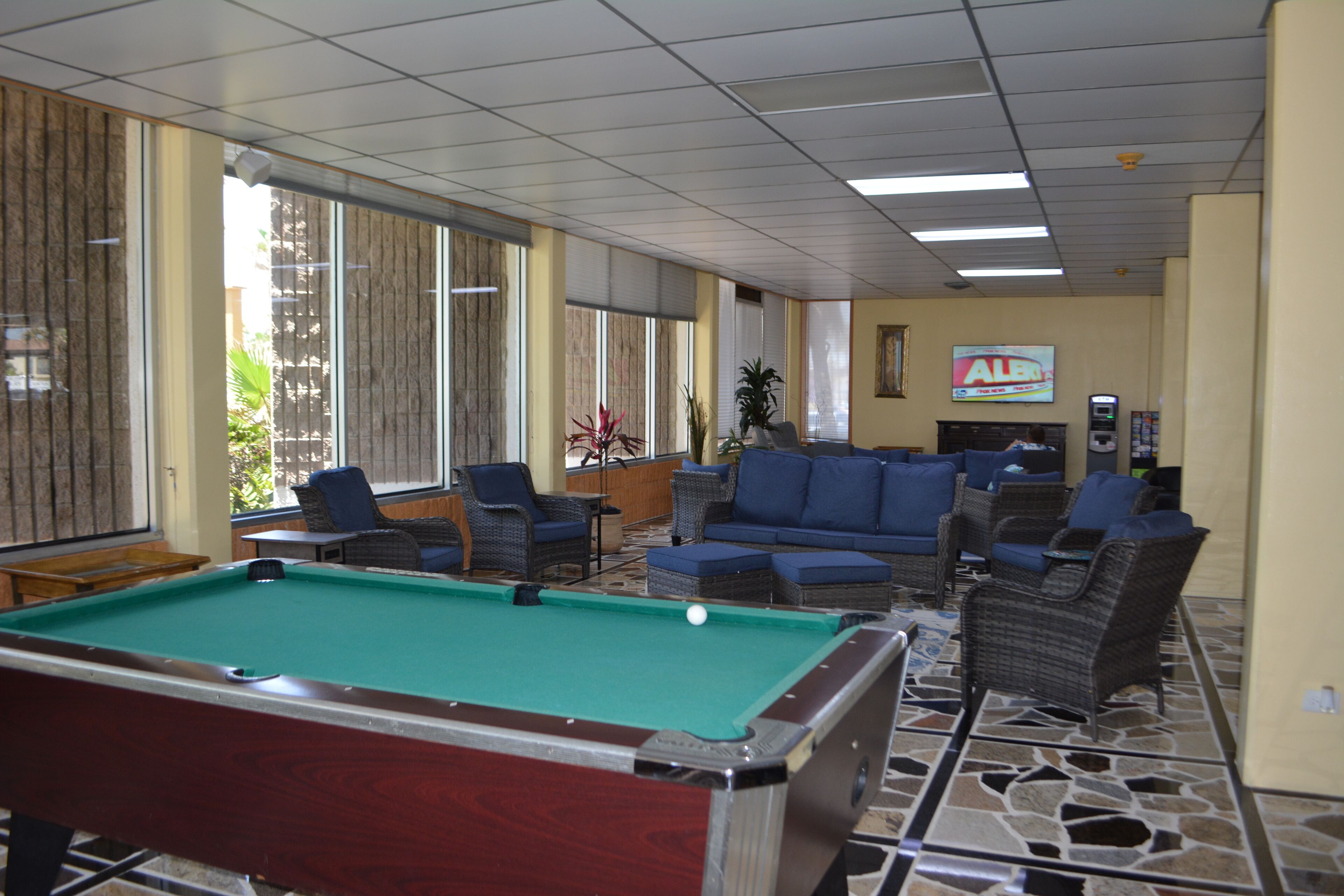 A pool table in a room with seating and a television.