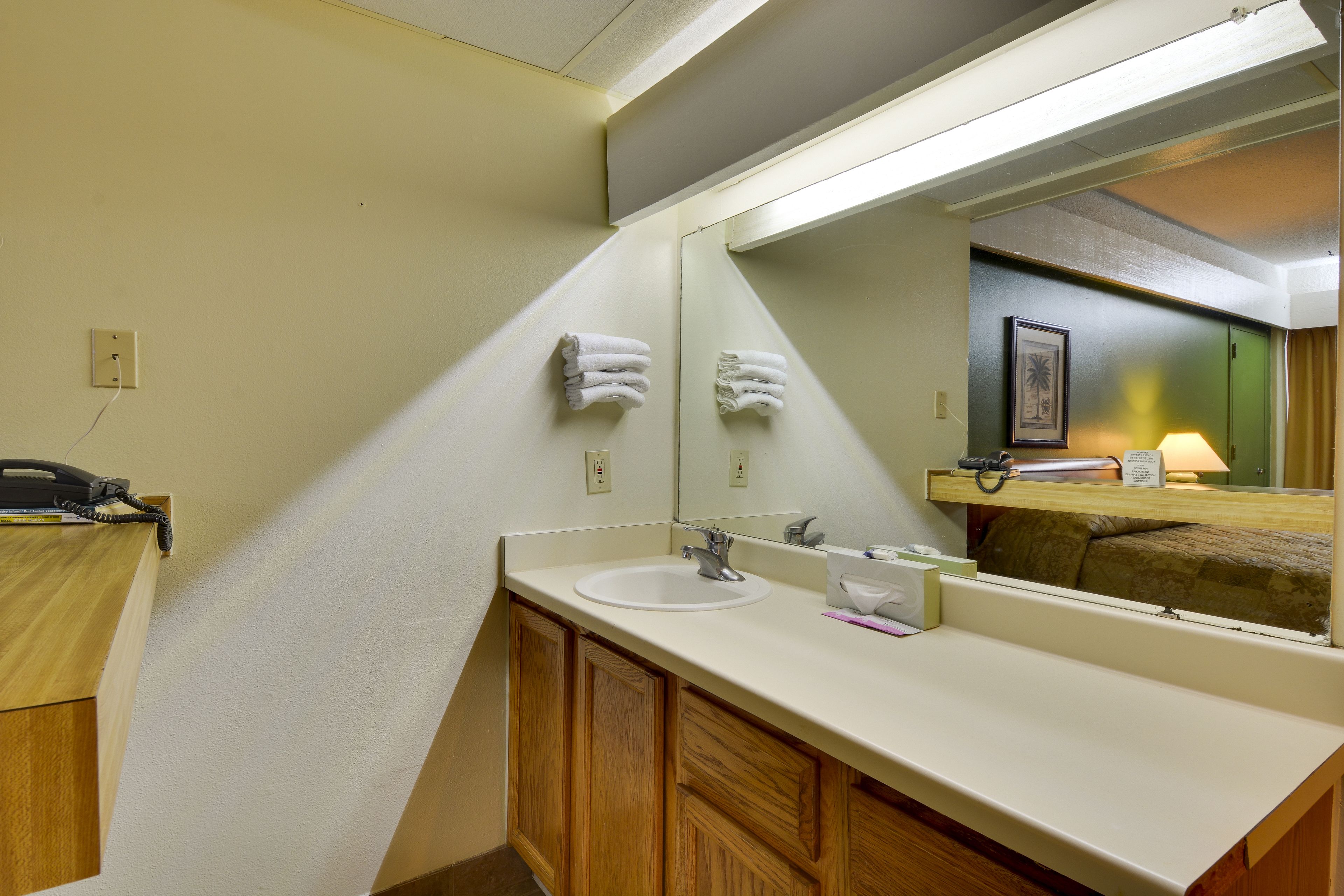 A bathroom with a sink, mirror, and wooden cabinets.