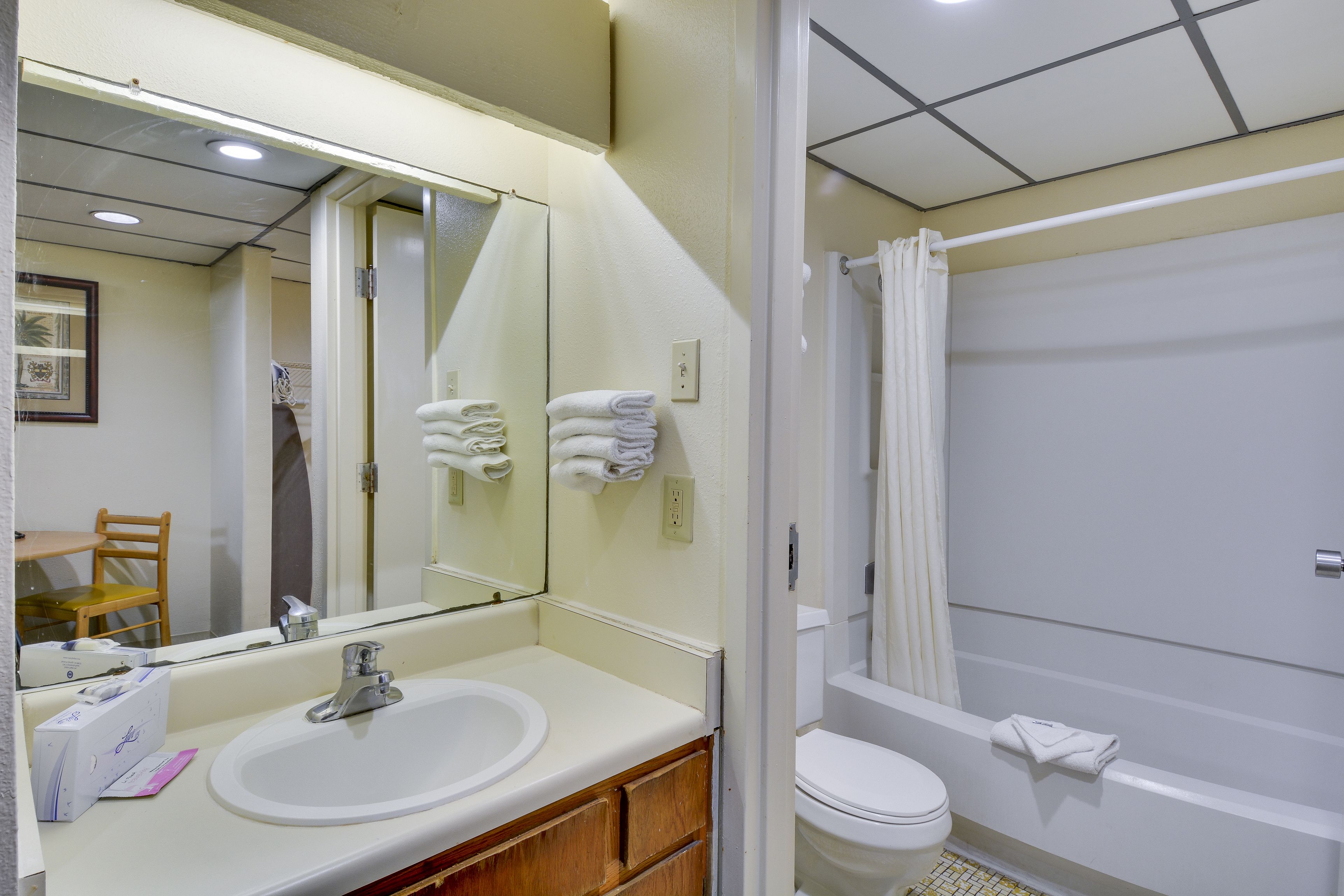 A bathroom with a sink, mirror, toilet, and bathtub.