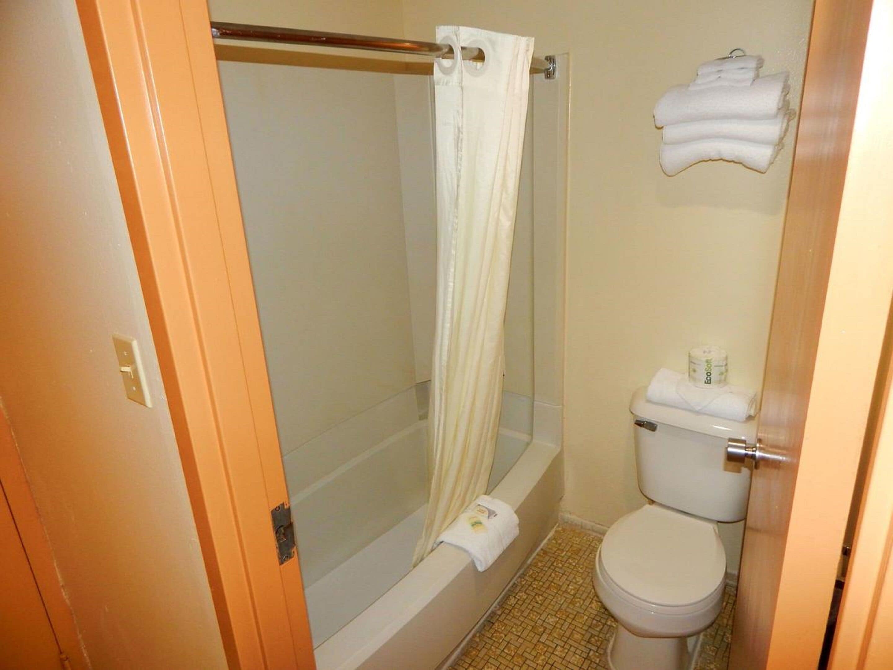 Un baño con ducha, inodoro y perchero para toallas.