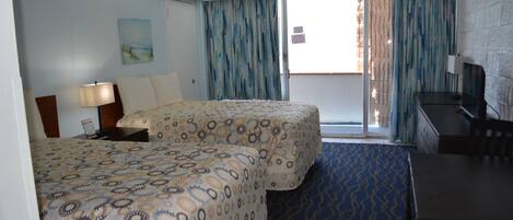 A hotel room with two beds, a desk, a chair, a TV, and a window with curtains.