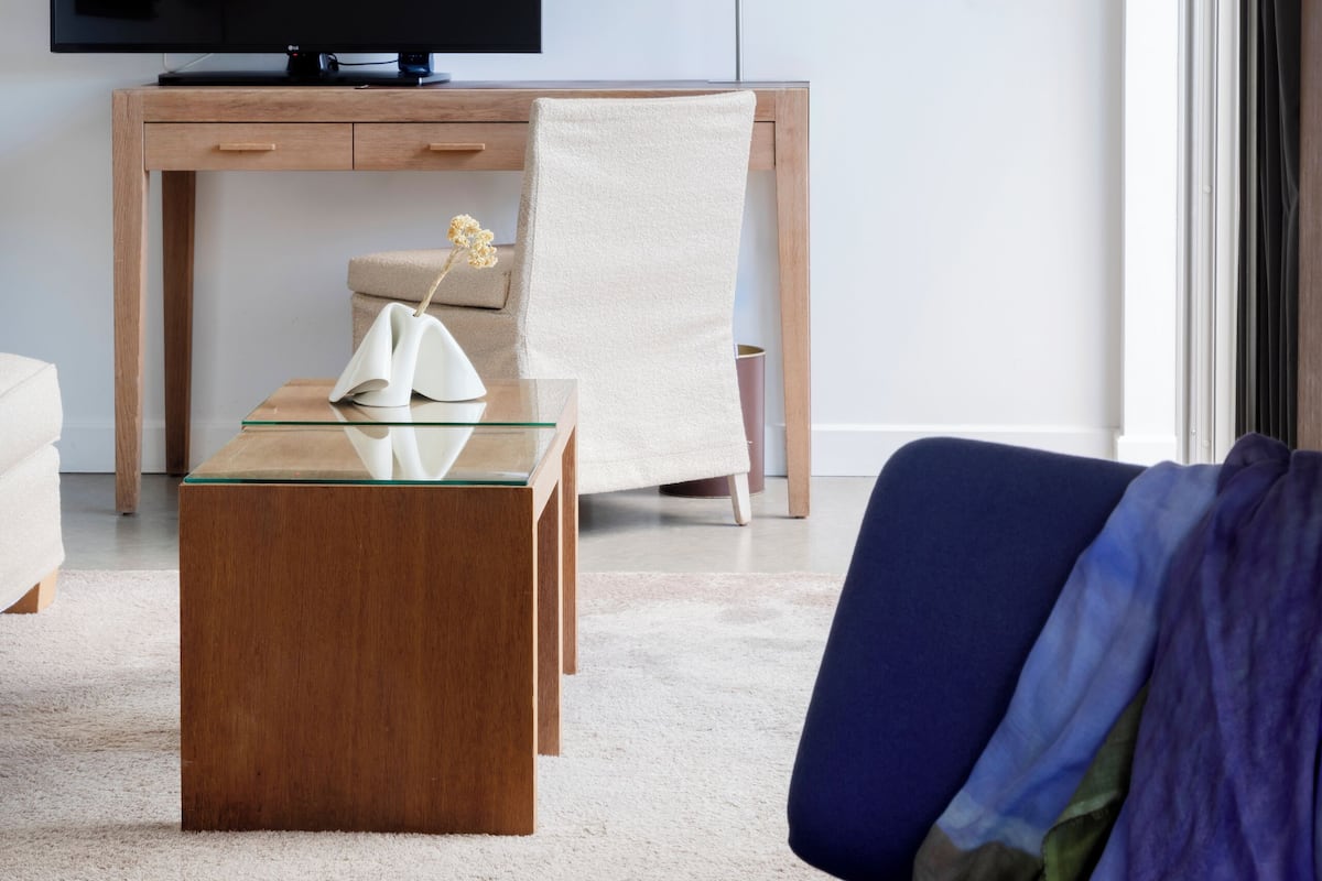 A modern living room with a flat-screen TV, a wooden desk, a chair, a sofa, and a lamp.