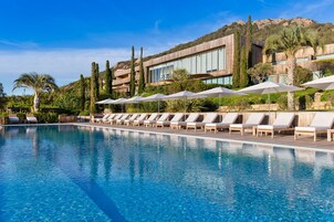 Una piscina al aire libre, sombrillas, sillones reclinables de piscina