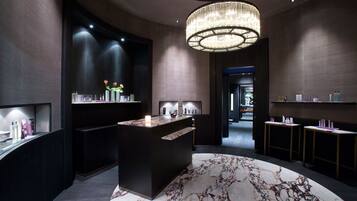 Experience the sophisticated lobby with a central reception desk, circular chandelier, and marble-patterned rug.