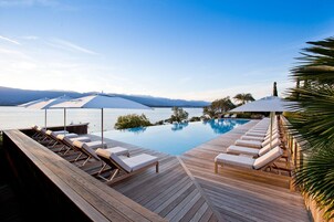 Una piscina al aire libre, sombrillas, sillones reclinables de piscina