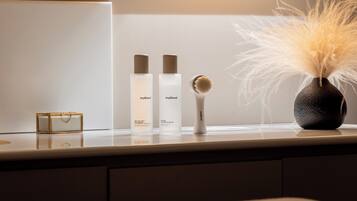 Un meuble-lavabo de salle de bain avec un miroir, un petit récipient rectangulaire et trois flacons de produits de soins pour la peau.