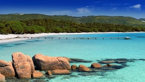 A beach with clear turquoise water, a wooden pier, and rocky outcrops. - Casadelmar (Porto-Vecchio)