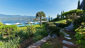 A landscaped garden with a stone pathway, a pool, and umbrellas. - Casadelmar (Porto-Vecchio)