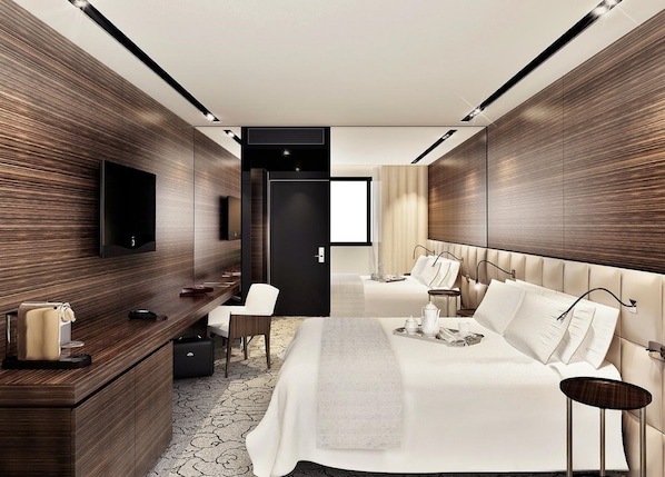 Una habitación de hotel moderna con una cama grande, un escritorio con una silla, un televisor y un armario.
