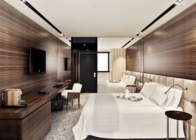 Una habitación de hotel moderna con una cama grande, un escritorio con una silla, un televisor y un armario.