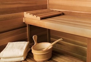 A wooden sauna with a bench, a wooden bucket with a ladle, and a towel on the floor. - Howard Hôtel Paris Orly Aeroport (Paray-Vieille-Poste)