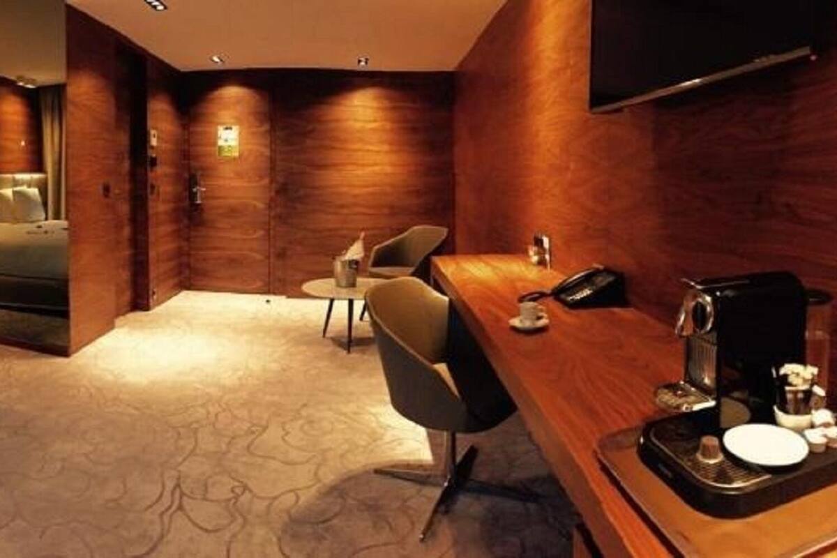 Une chambre d’hôtel moderne avec un grand lit, un bureau doté d’une machine à café et une chaise.