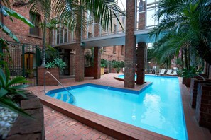 Una piscina al aire libre, sillones reclinables de piscina