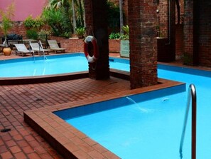 Una piscina al aire libre, sillones reclinables de piscina