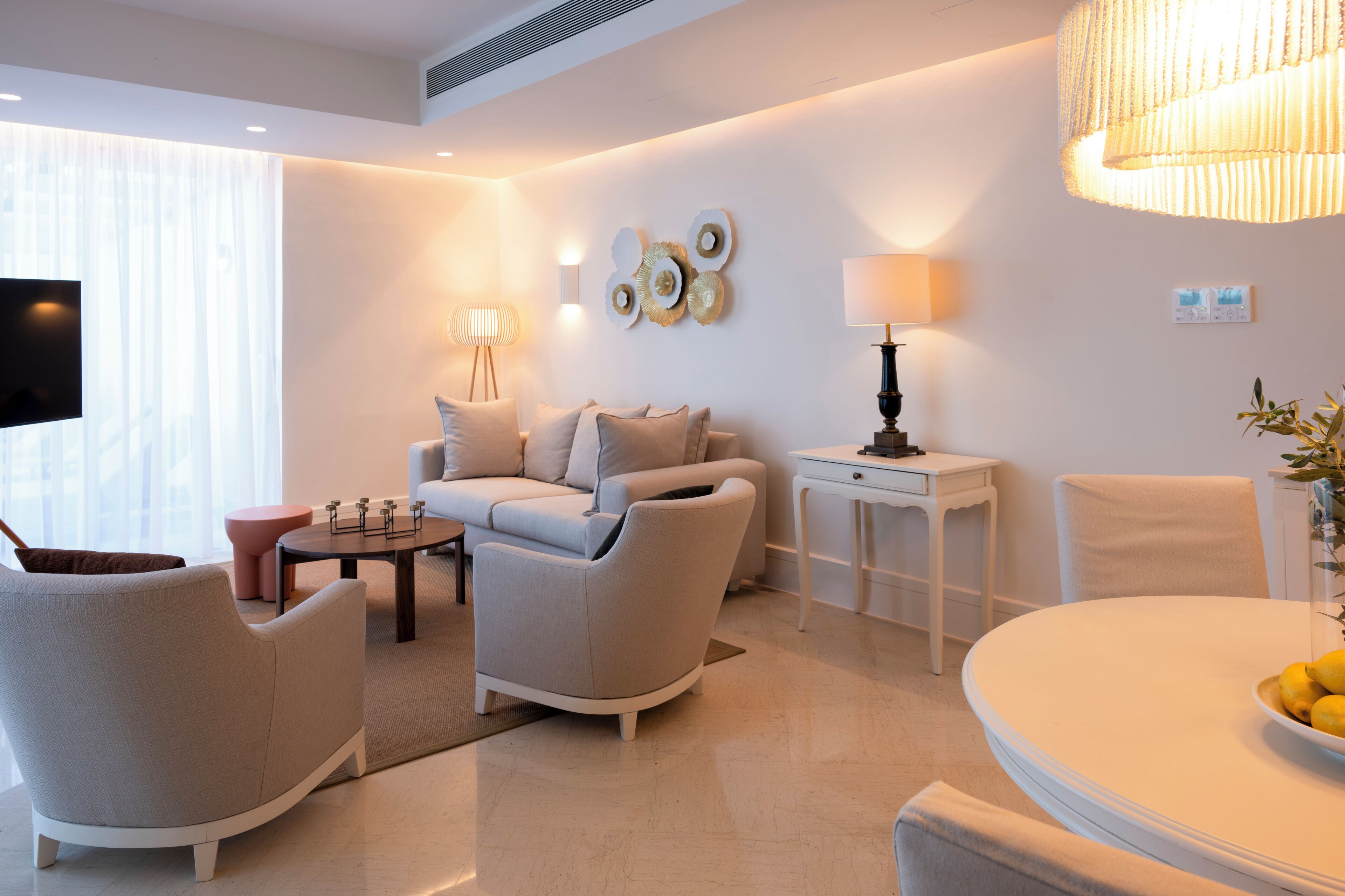 Een moderne woonkamer met een bank, fauteuils, een salontafel en een eettafel.