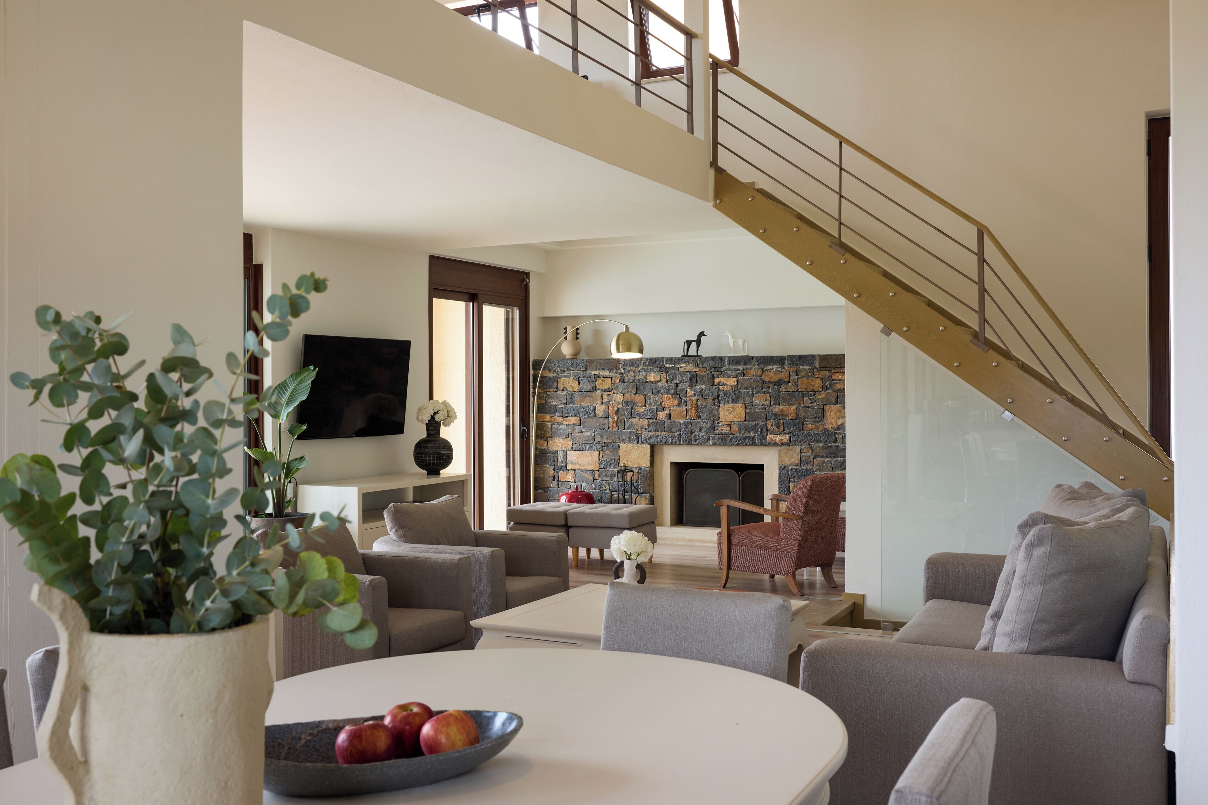 Una sala de estar con chimenea de piedra, una escalera y un comedor con un frutero.