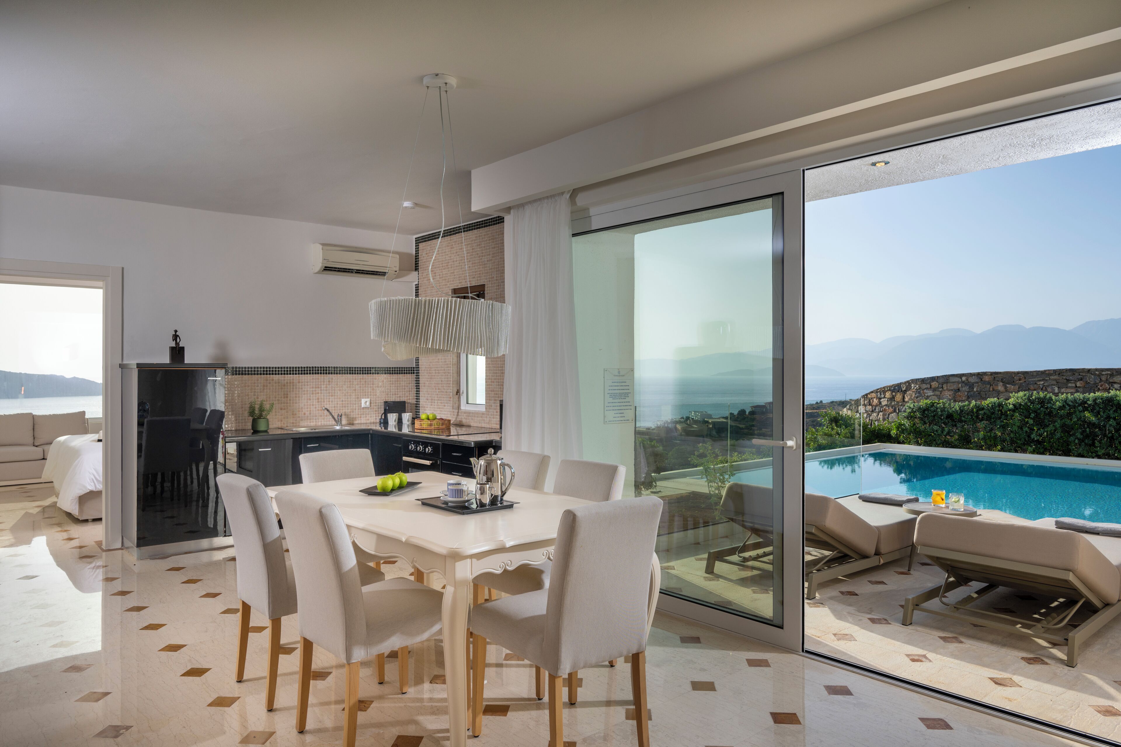 A modern kitchen with a dining area and a poolside lounge.
