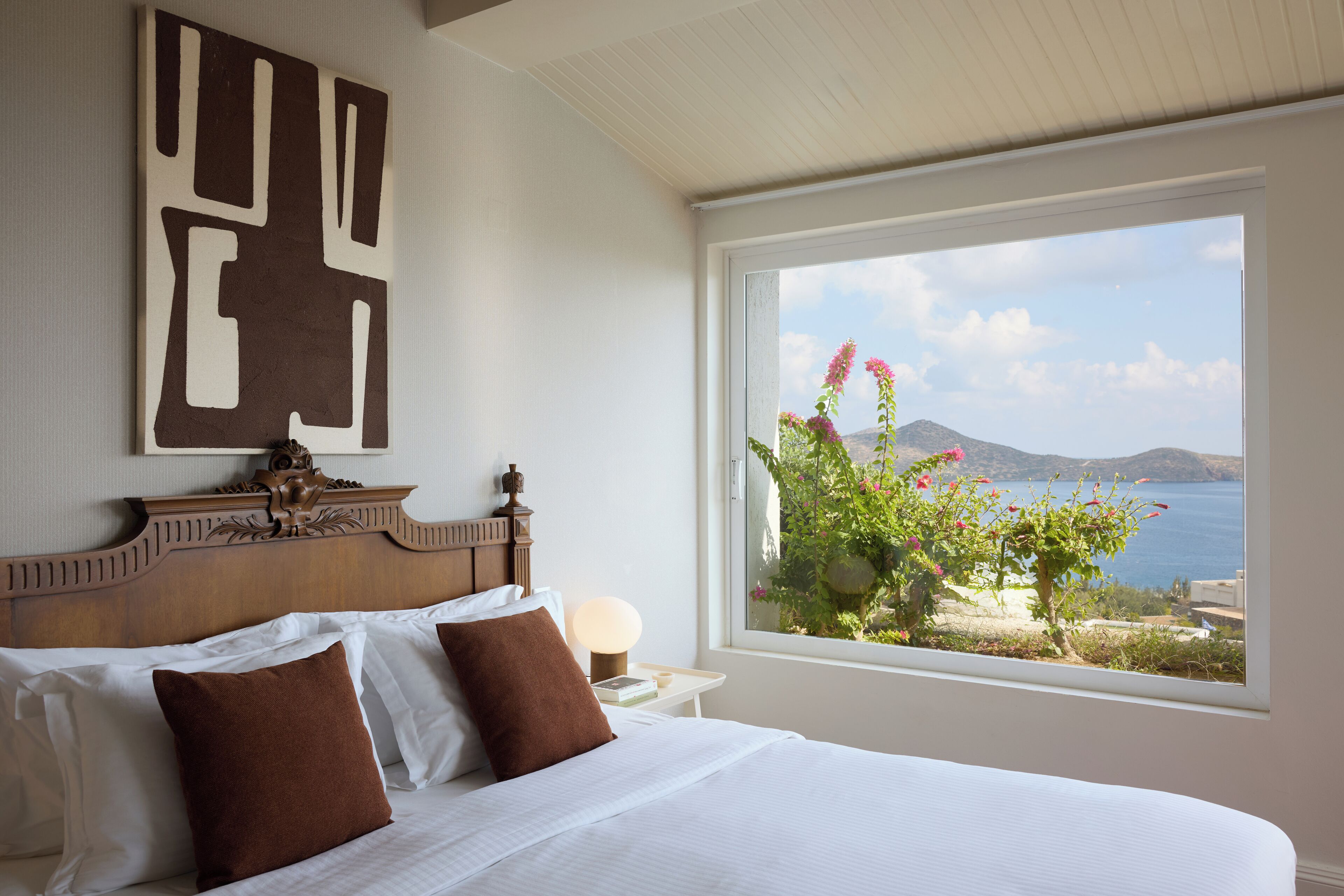 Una camera d'hotel con un letto grande, vista mare e un elemento decorativo al muro.