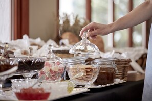 A buffet table with various food items and a hand reaching for a glass container. - Elounda Gulf Villas by Sandglass (Agios Nikolaos)