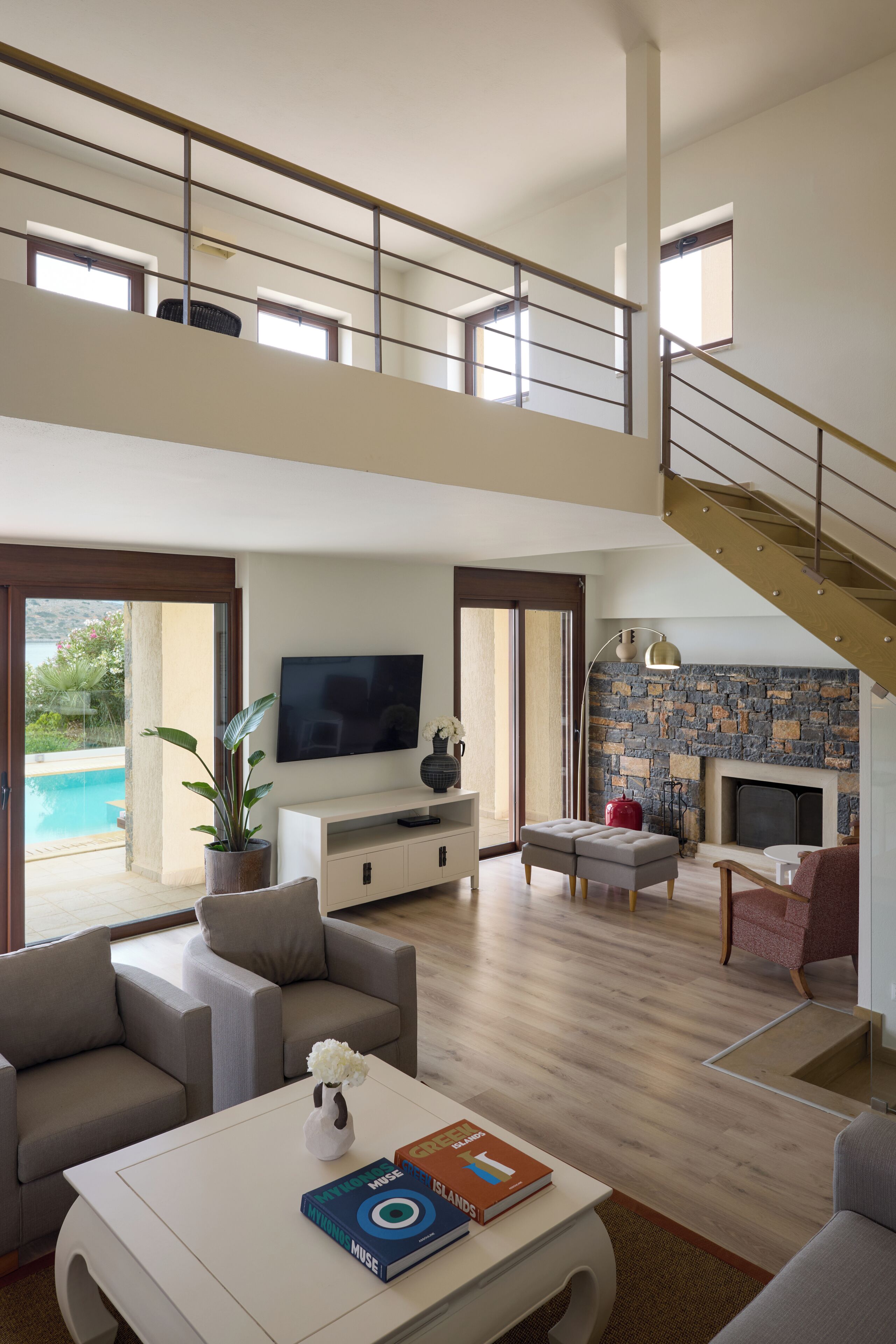 Un amplio salón con televisión, asientos, chimenea y una escalera.