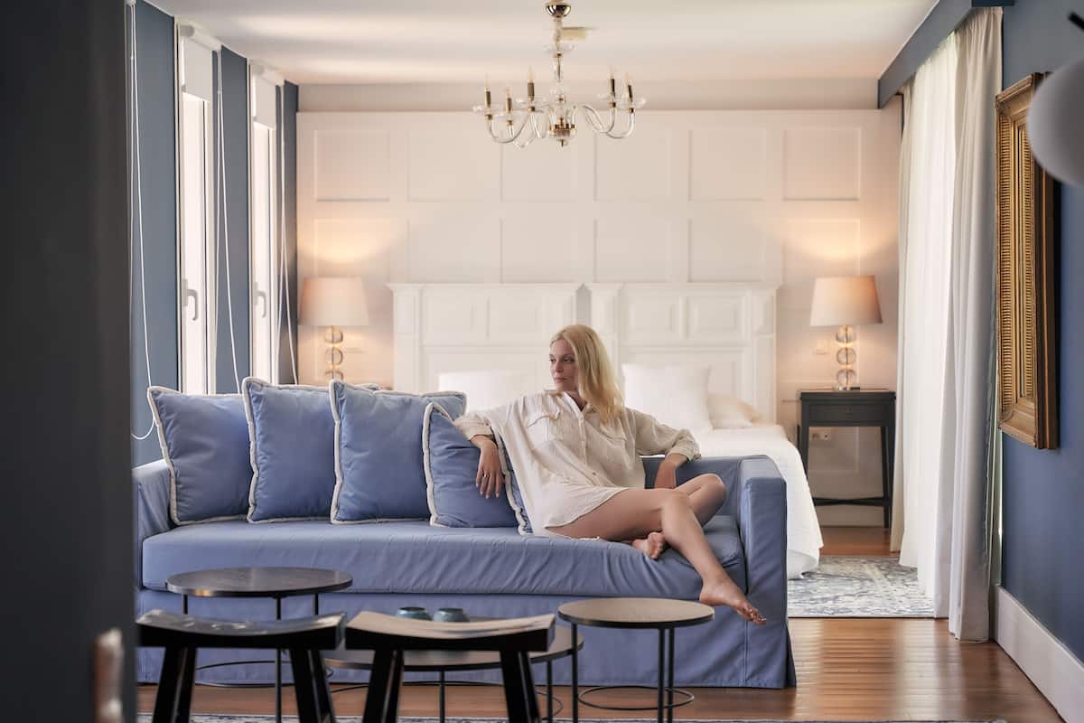 A modern bedroom with a large bed, a blue sofa, and two small tables.
