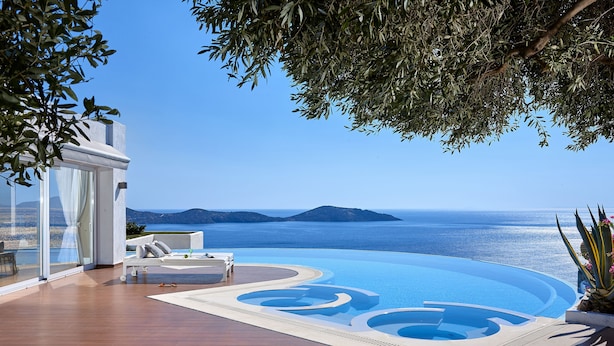 A pool area with a view of the sea and mountains.