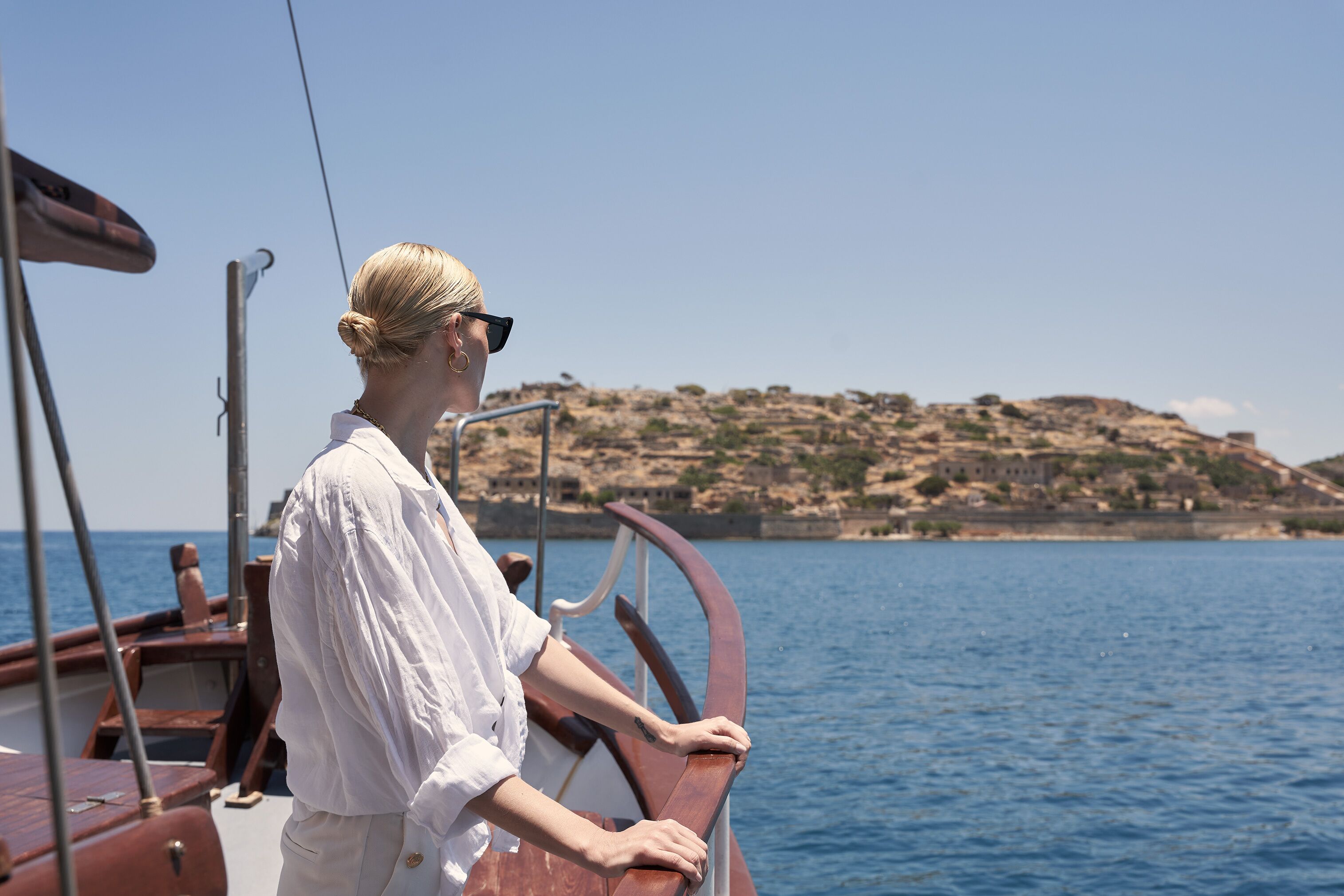 A person on a boat with a view of a rocky coastline.