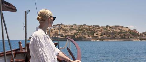 A person on a boat with a view of a rocky coastline.