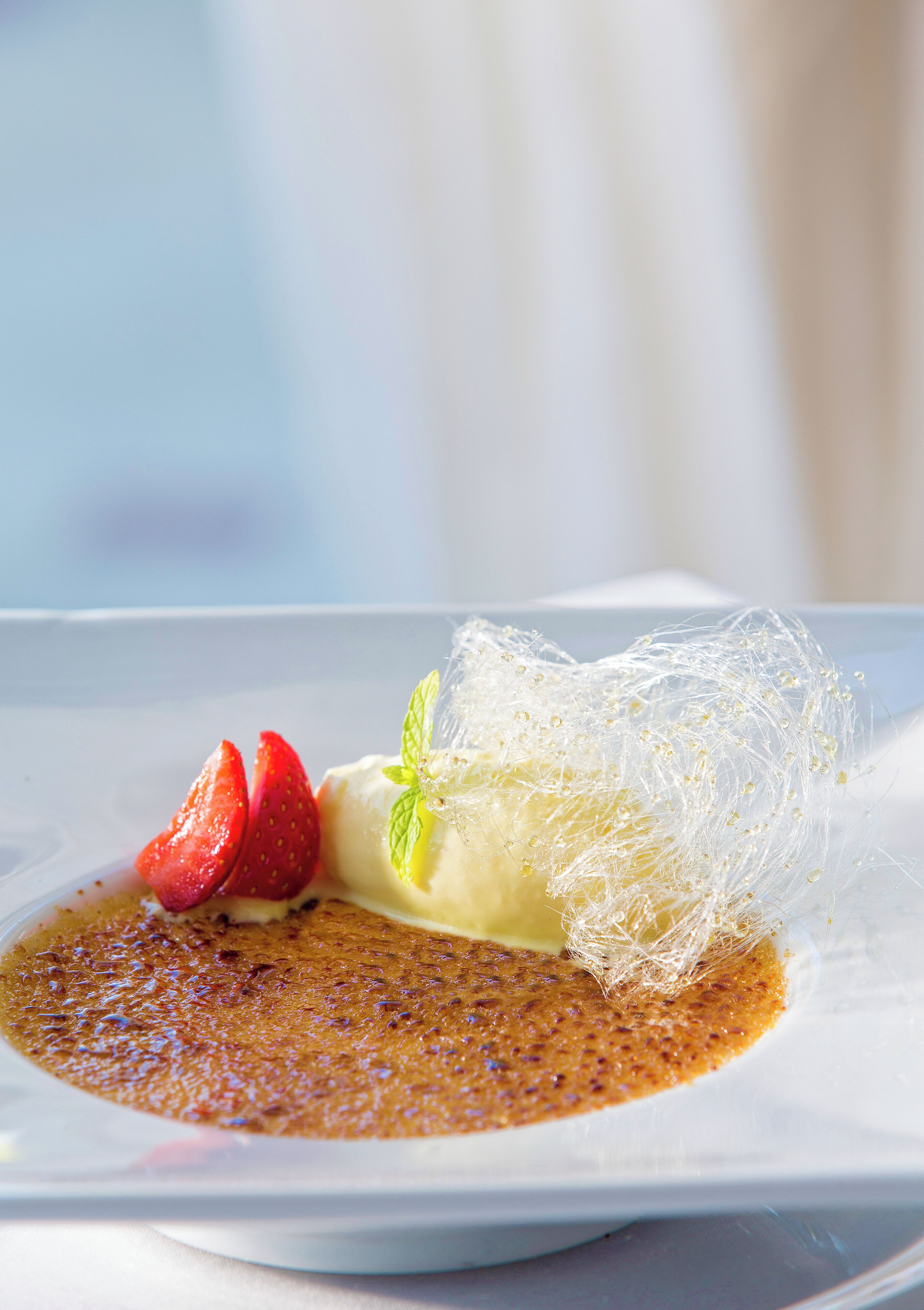 Un postre con fresas y una hoja de menta sobre un plato.