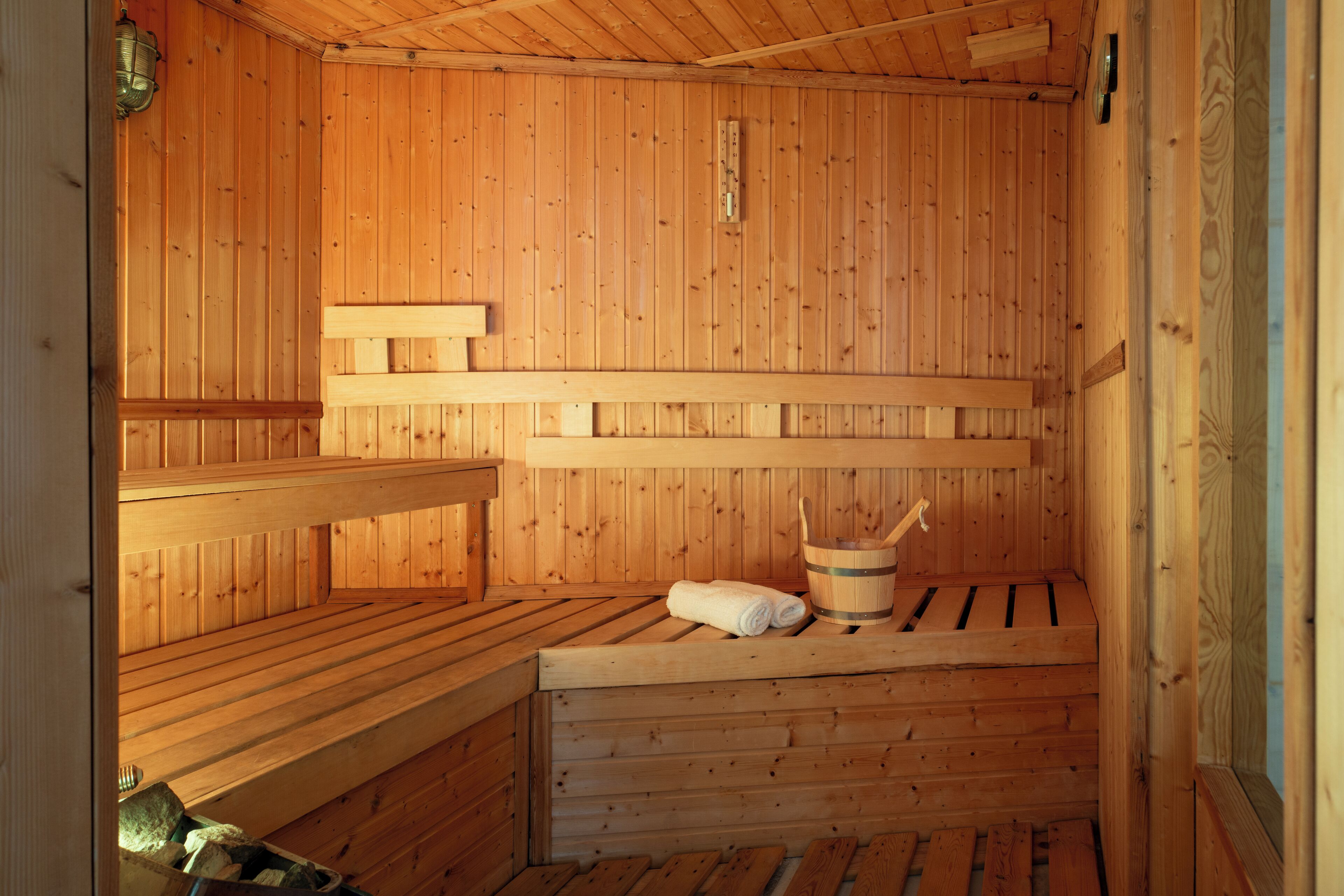 A wooden sauna with benches and a bucket.