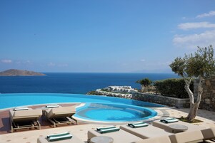 Zona junto a la piscina con sillones de descanso y vista al mar.
