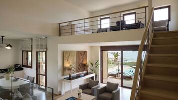 Un salón espacioso con balcón, comedor y vista al mar.