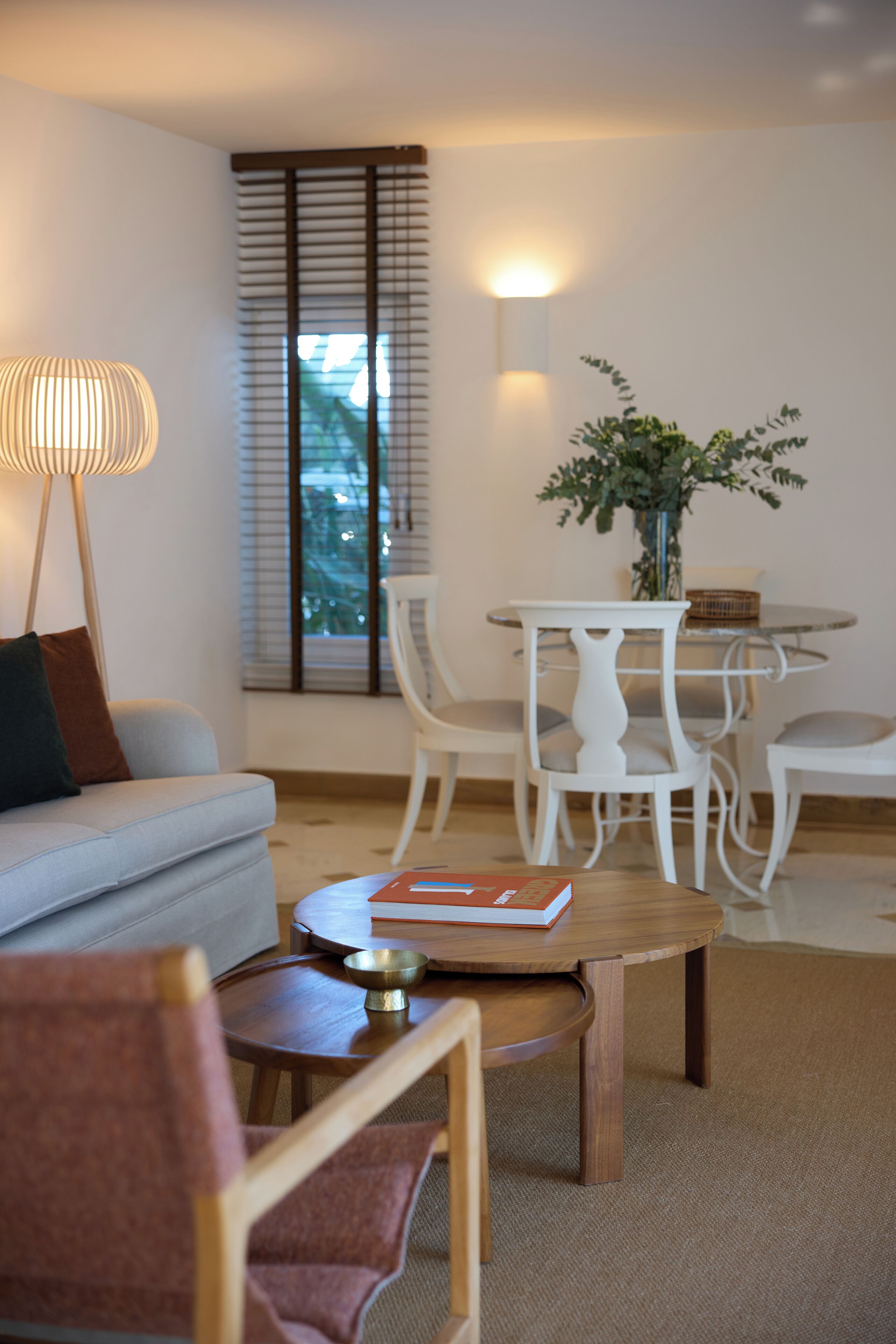 A modern living room with a sofa, a coffee table, and a dining area with chairs and a table.