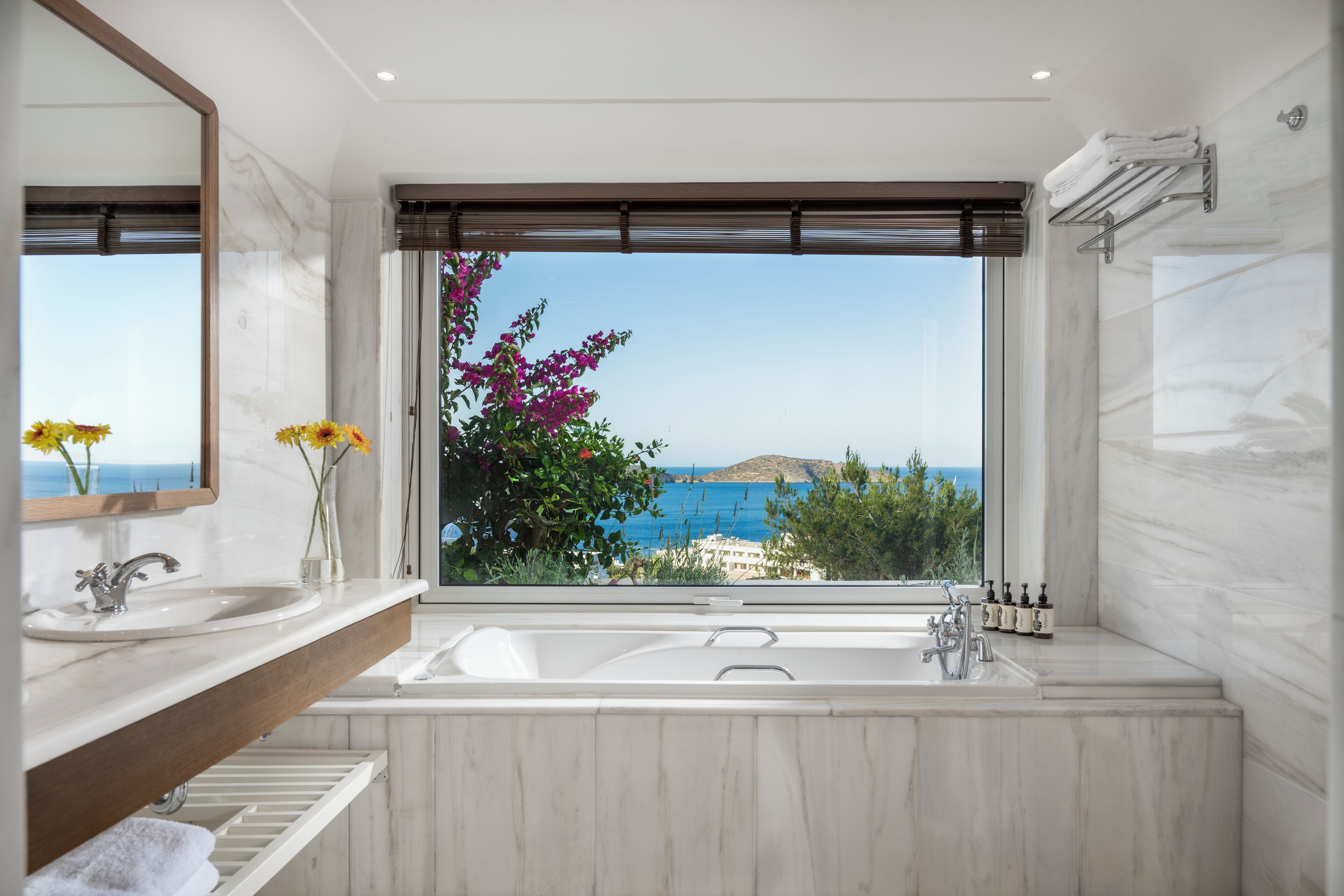 A modern bathroom with a large window, a bathtub, and a vanity with a mirror.