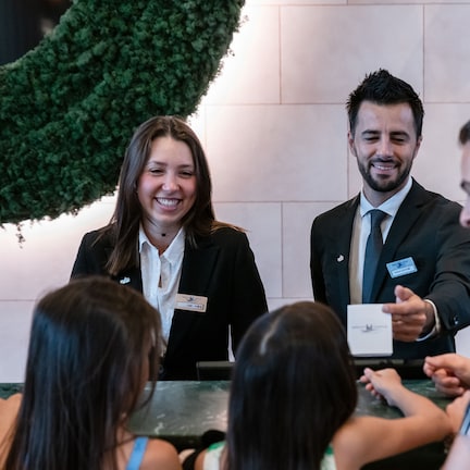 A group of people in a meeting room with a green wall and a whiteboard.