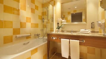 Une salle de bain avec une baignoire, un meuble-lavabo avec un miroir et un espace douche.