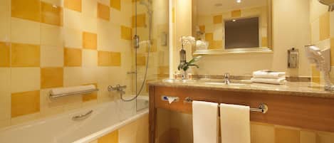 Un baño con bañera, tocador con espejo y zona de ducha.