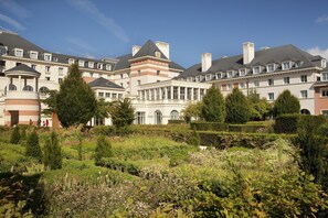 Un hotel grande con varias edificaciones, un jardín bien cuidado y un cielo despejado.
