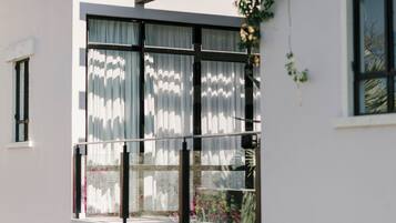 Un edificio moderno con grandes ventanales, un balcón y vistas a flores rosadas.