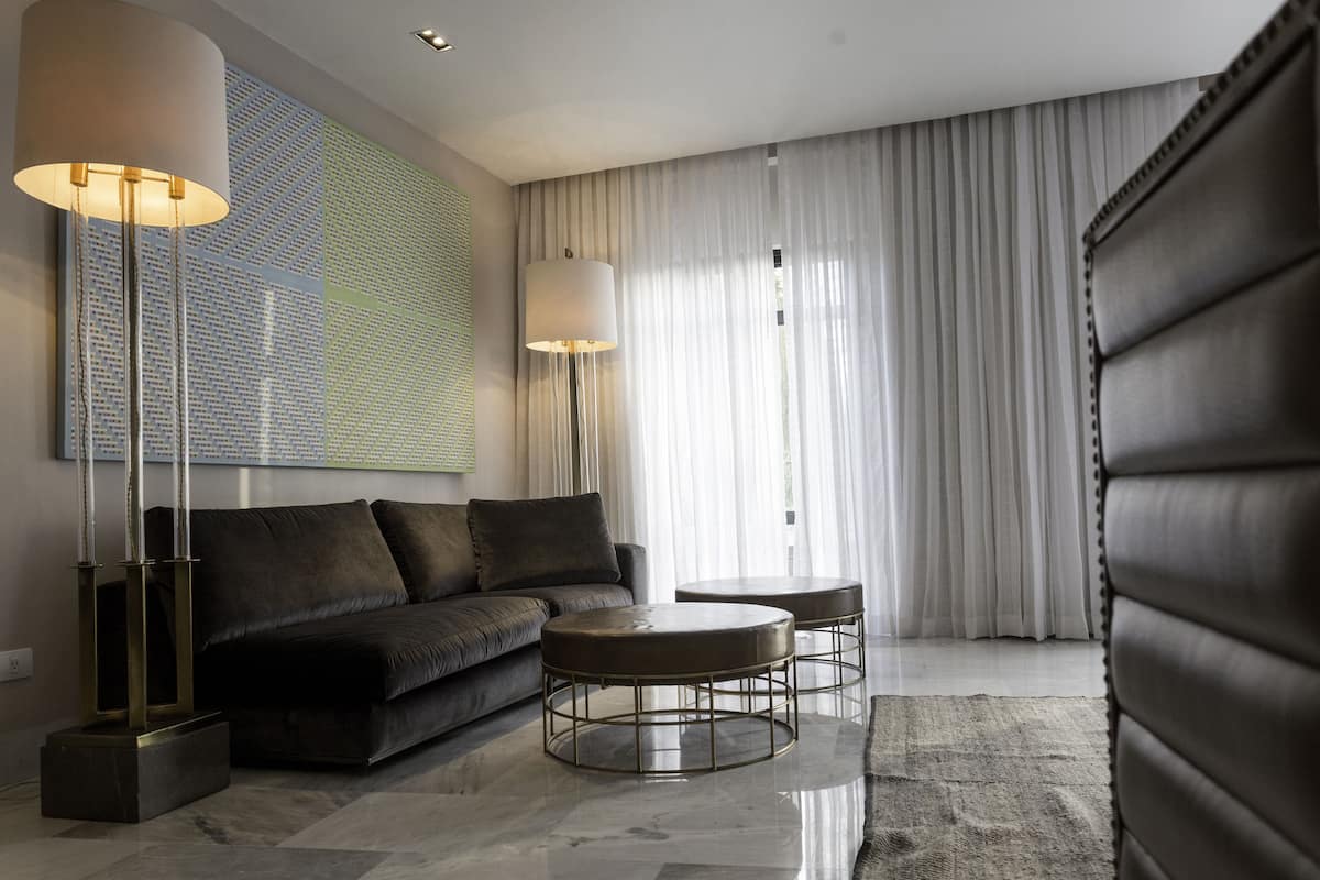 A modern living room with a dark leather sofa, two round coffee tables, and a large abstract painting on the wall.