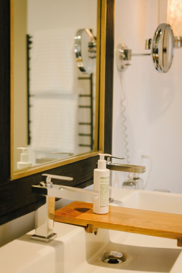 Un baño con tocador de madera, un lavamanos blanco, un espejo y un cabezal de ducha de mano.
