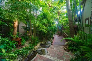 Un rigoglioso giardino interno con un sentiero in pietra che conduce a un ponticello di legno.