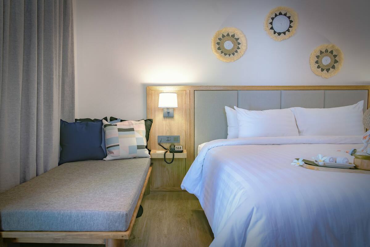 A hotel room with two beds, a nightstand with a lamp, and decorative wall art.