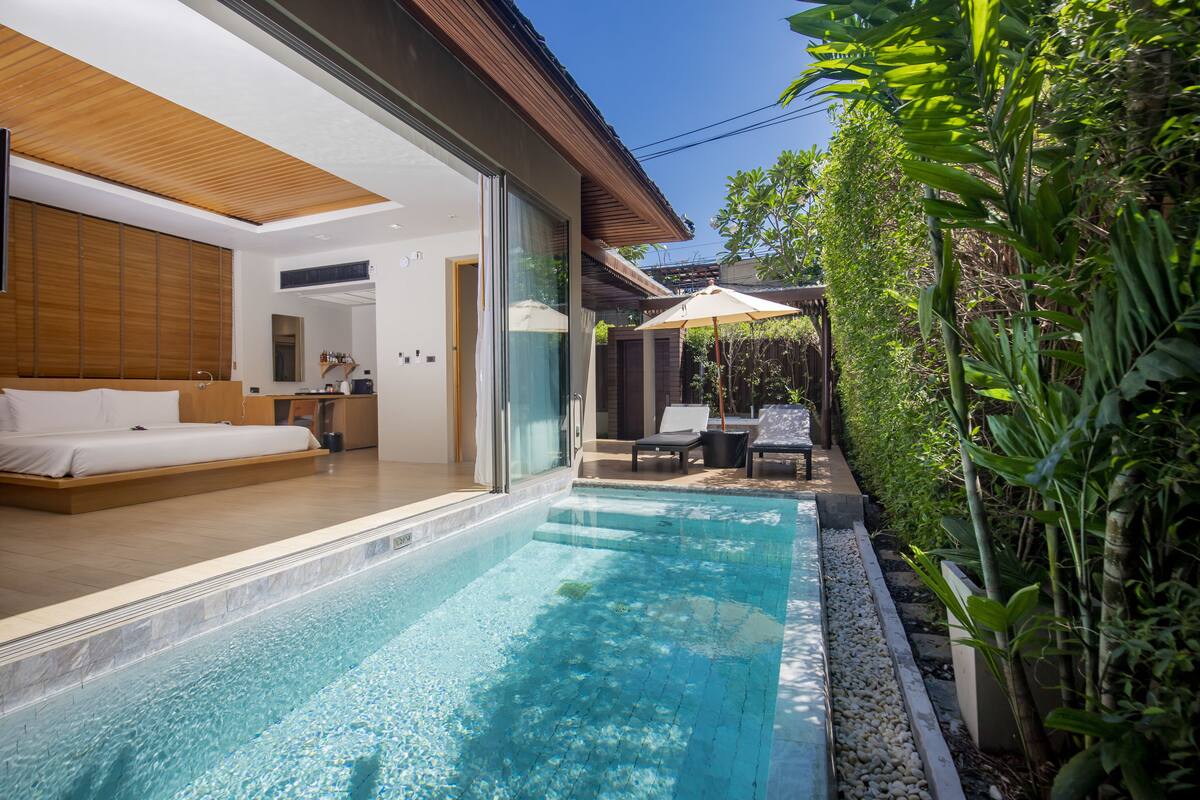 A modern hotel room with a large bed, a bathroom, and a view of a swimming pool.